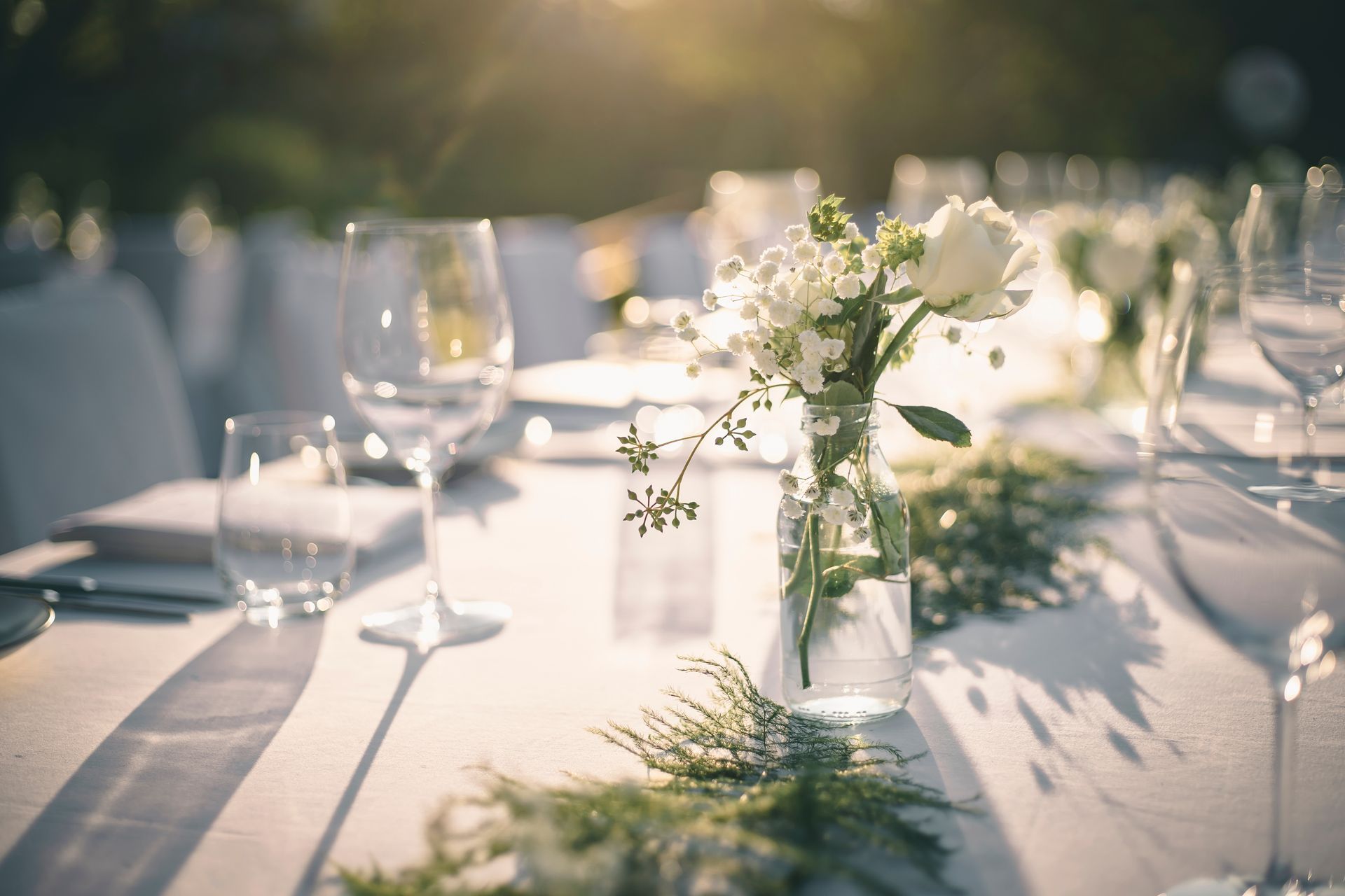 Wedding reception table setting with white flowers and greenery.