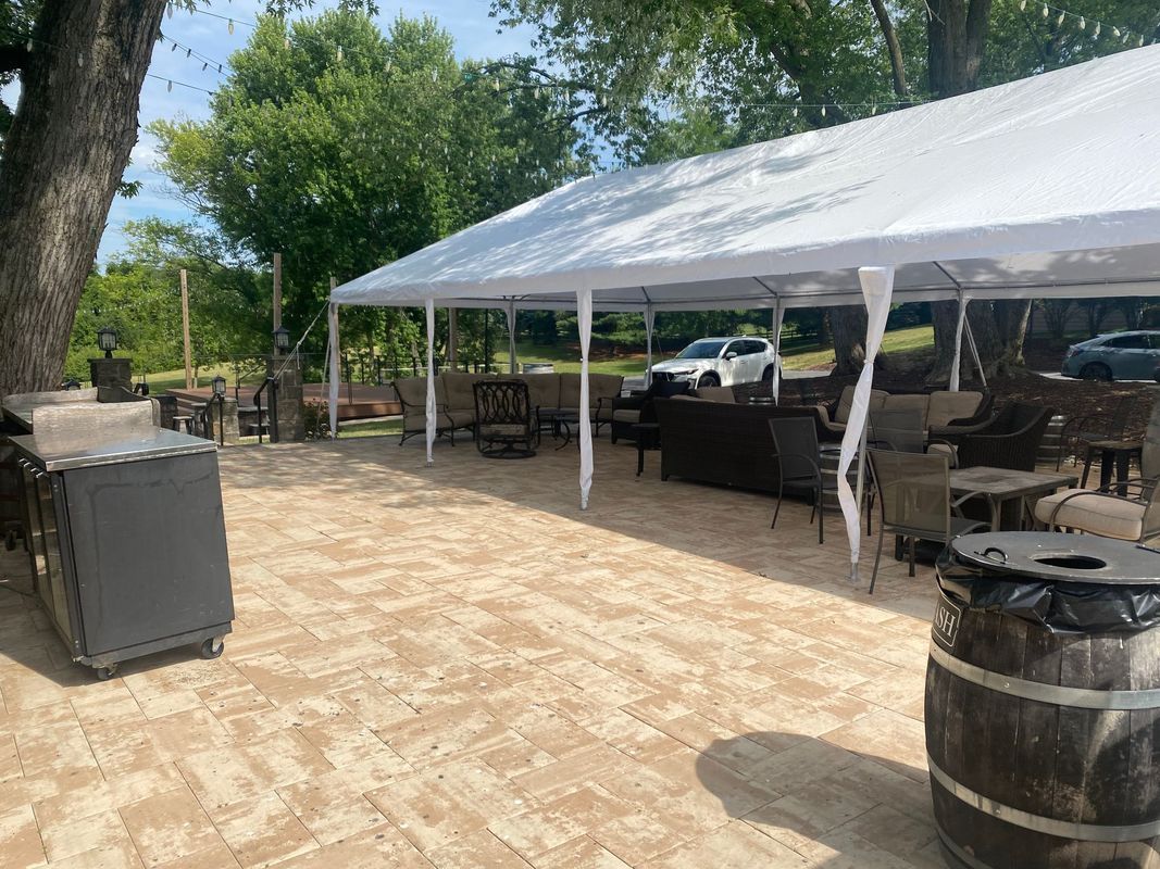 Outdoor patio with tent, furniture, and a grill. Sunny day.