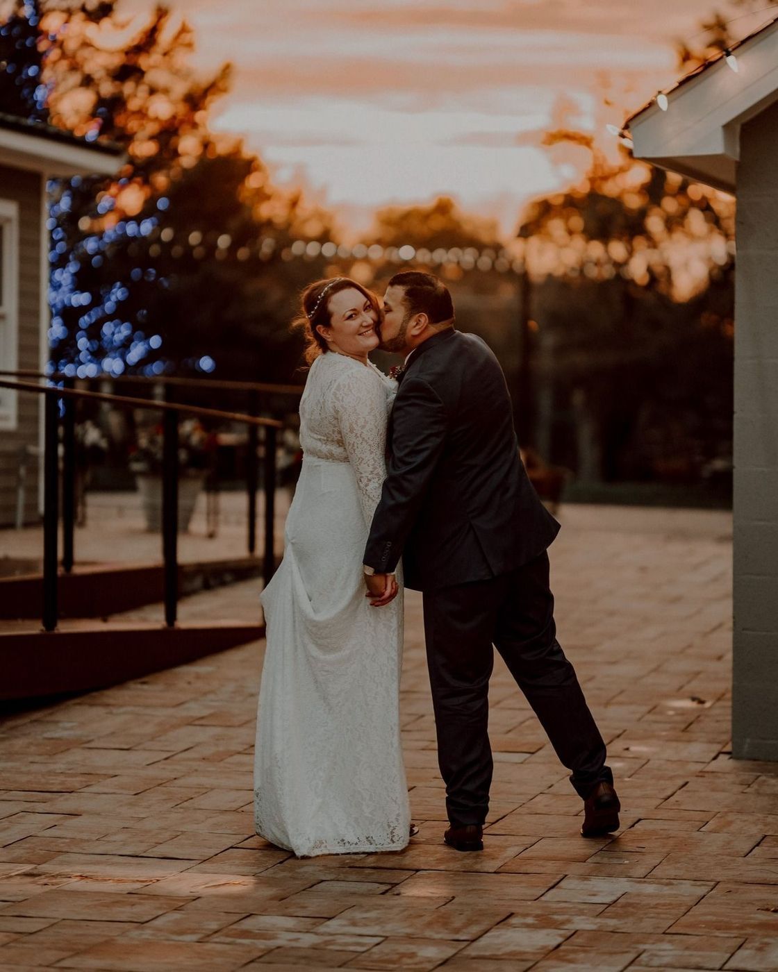 Newlyweds embrace. Man kisses woman on the cheek outside during sunset.