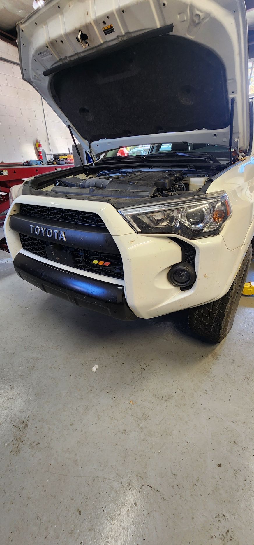 White Toyota SUV with hood up, in a garage. | Ish Auto Clinic