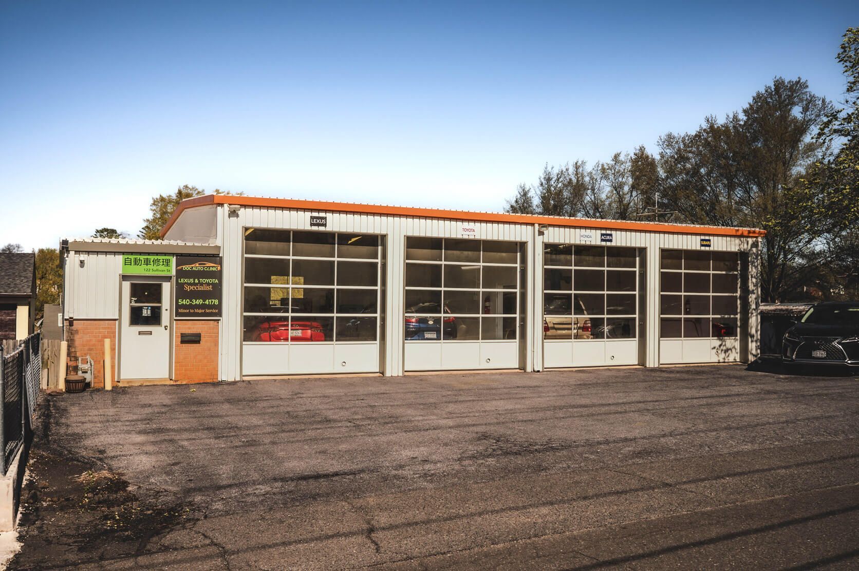 A mechanic shop with three bays. The building is white with glass garage doors. | Ish Auto Clinic