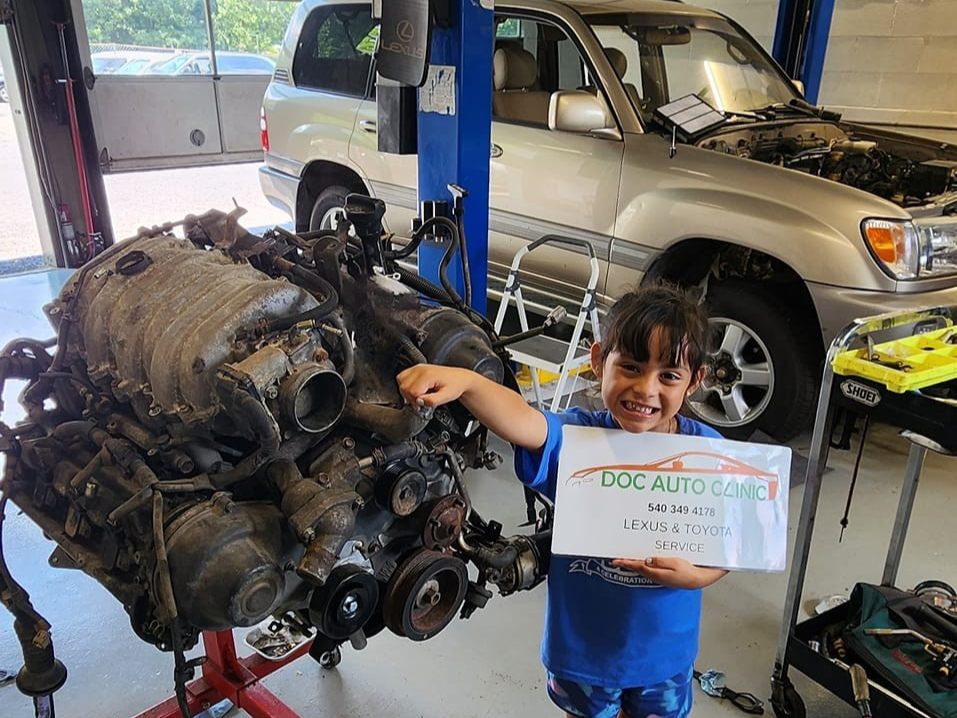 Boy smiles, pointing to a large car engine | Ish Auto Clinic