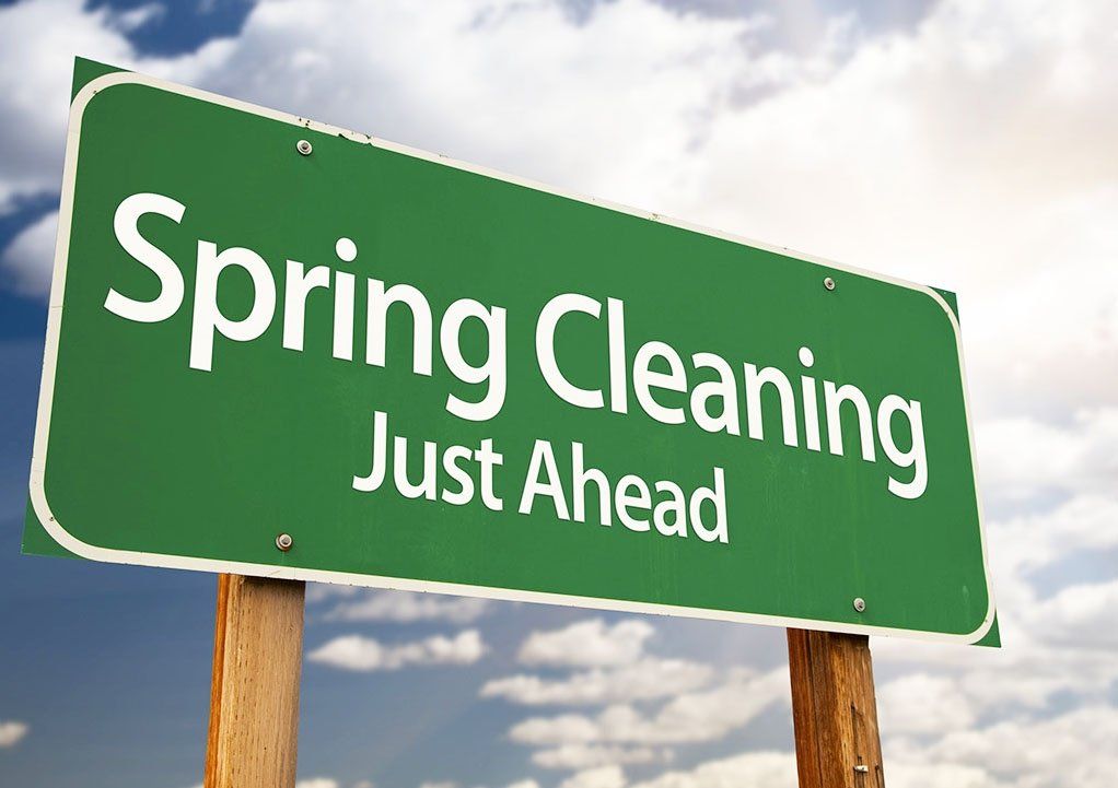 a green street sign that says spring cleaning just ahead
