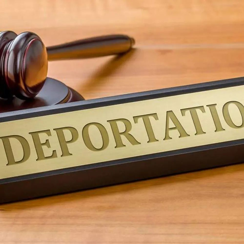 Gavel beside a sign reading “DEPORTATION” on a courtroom desk