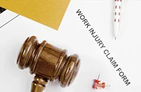 A wooden judge 's gavel is sitting on top of a work injury claim form.