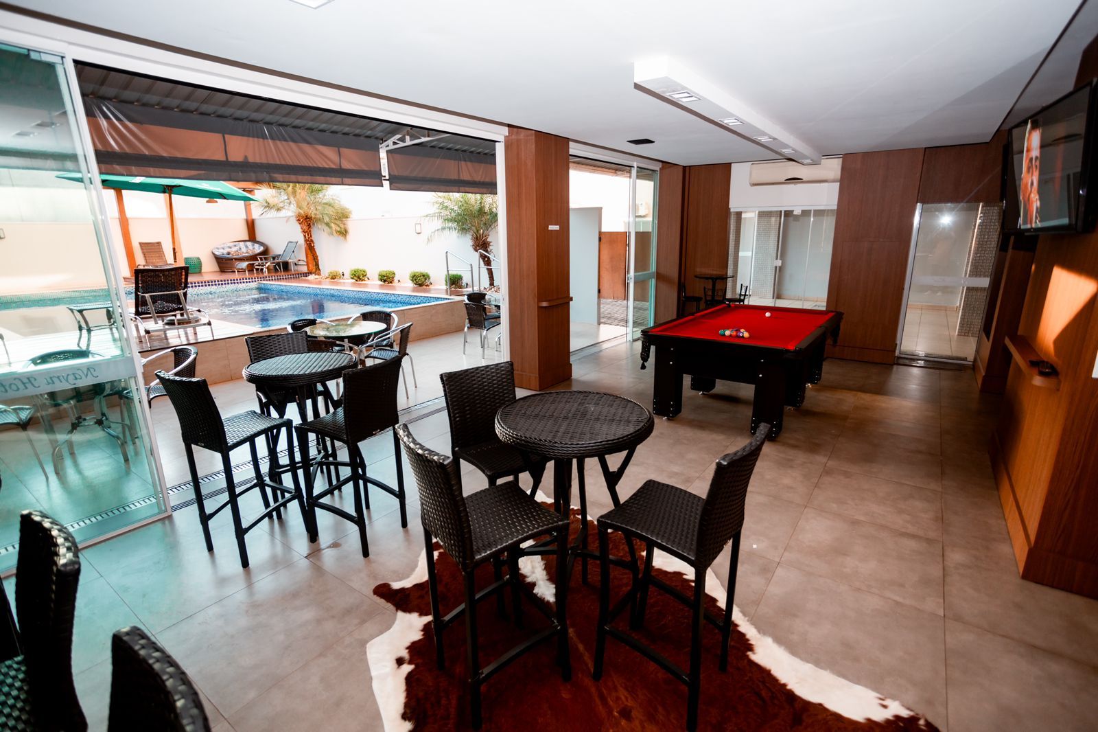 Uma mesa de sinuca está em uma sala com mesas e cadeiras.