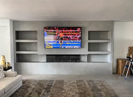 A living room with a fireplace and a flat screen tv on the wall.