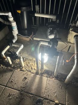 A light is shining on a bunch of pipes in a dark room.