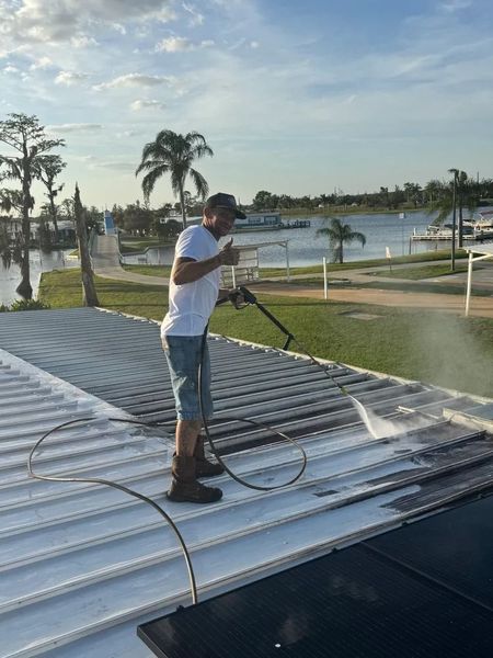 A man is cleaning the roof of a building with a high pressure washer.