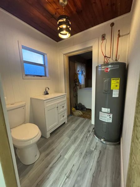 A bathroom with a toilet , sink , and water heater.