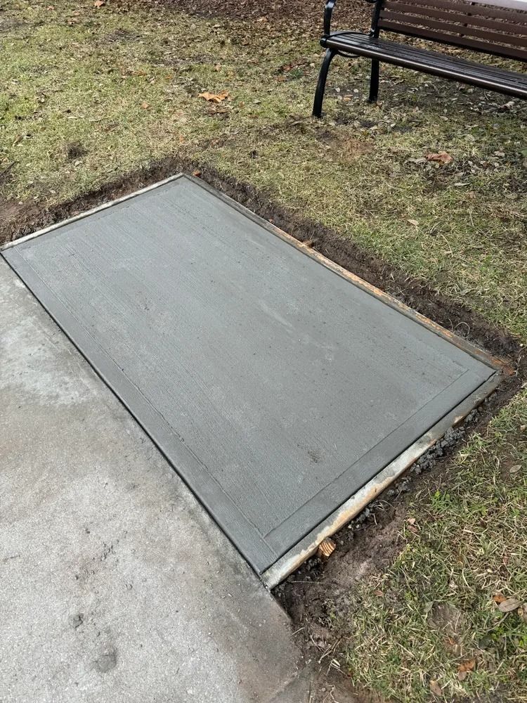 A concrete ramp is being built in a park next to a bench.