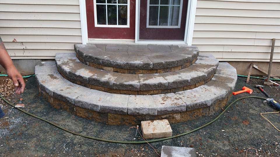 A person is working on a set of steps in front of a house.