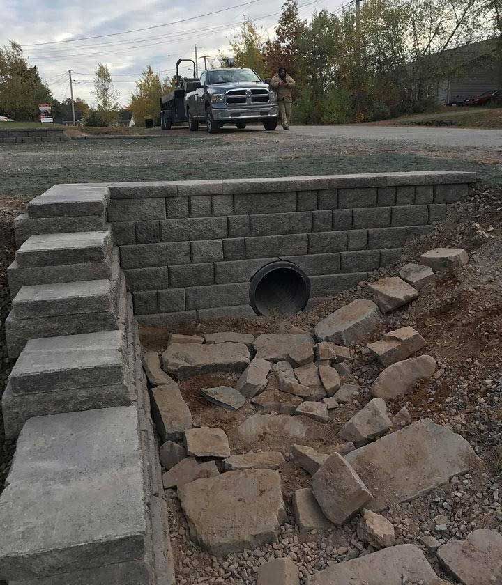 A truck is parked on the side of the road next to a brick wall.
