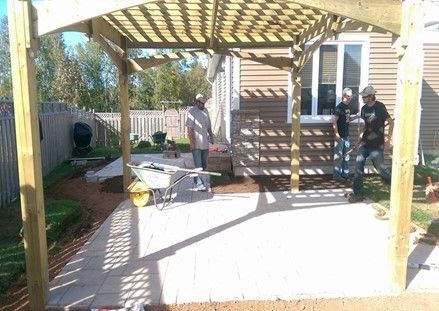 Worker is Standing Under a Wood Pergola – Calgary, AB – As The Sod Turns Landscape & Design Inc.