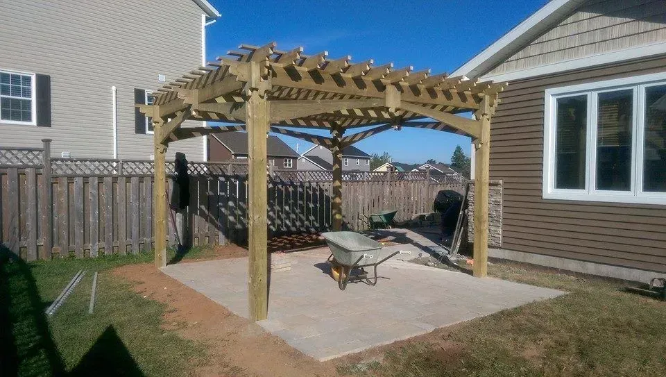 A wooden pergola is being built in the backyard of a house.
