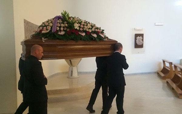 quattro necrofori che trasportano una bara