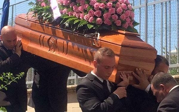 necrofori che trasportano un cofano funebre con composizione floreale