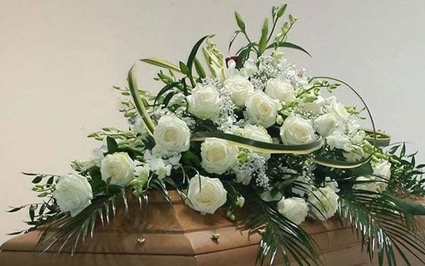 addobbo floreale con rose bianche su una bara