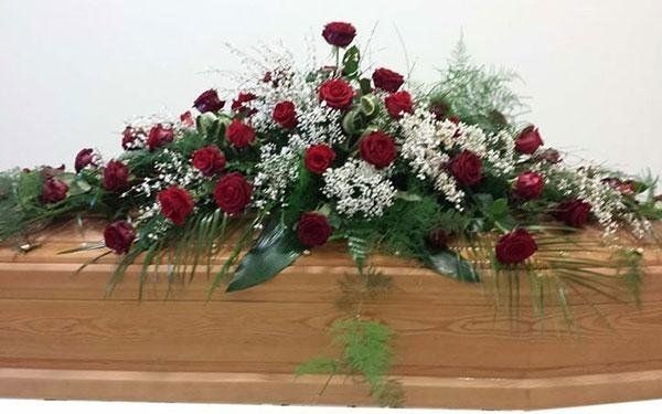 cofano funebre in legno con cuscino di fiori