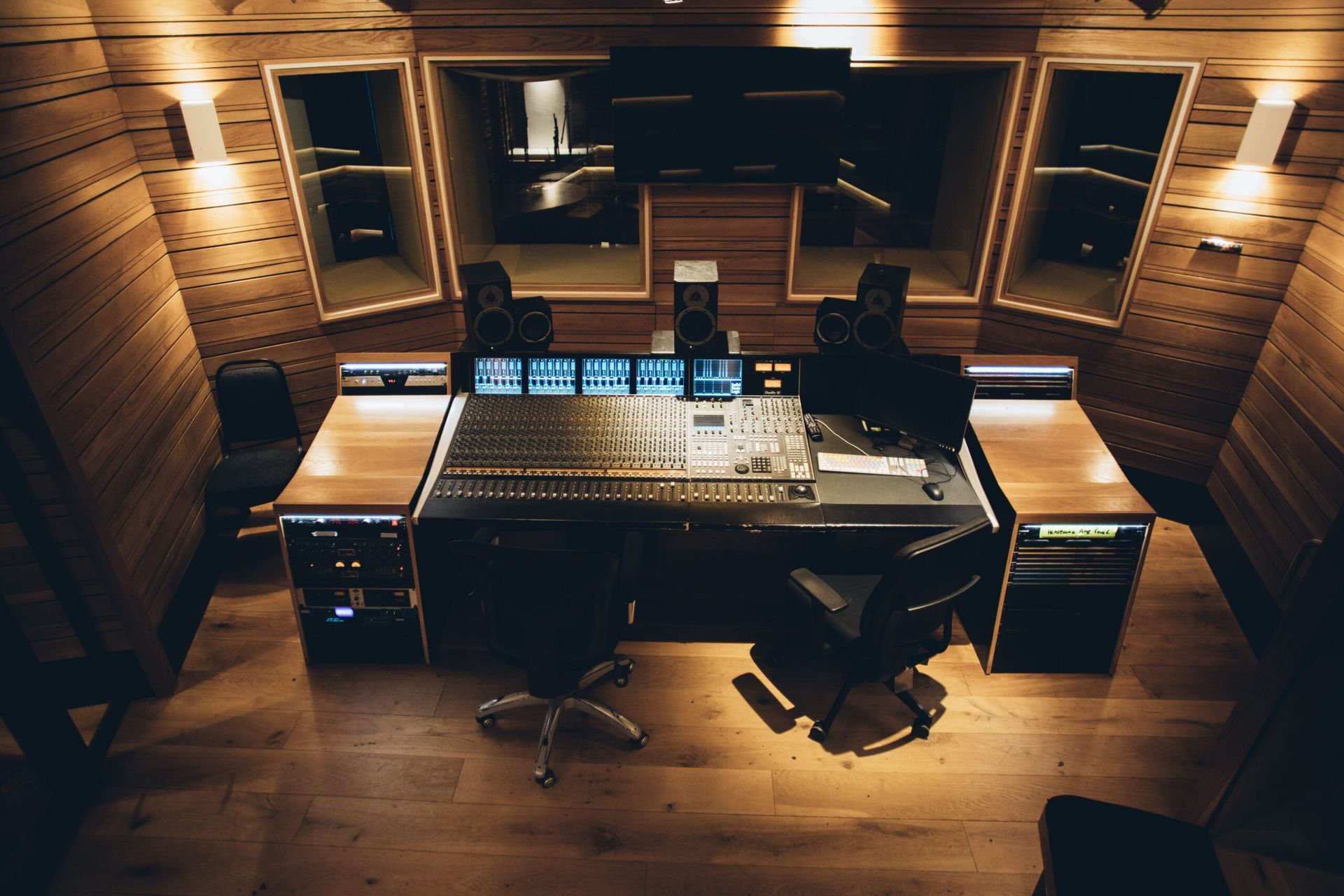 Recording studio control room, wood paneling, mixing console, monitors, dark lighting.