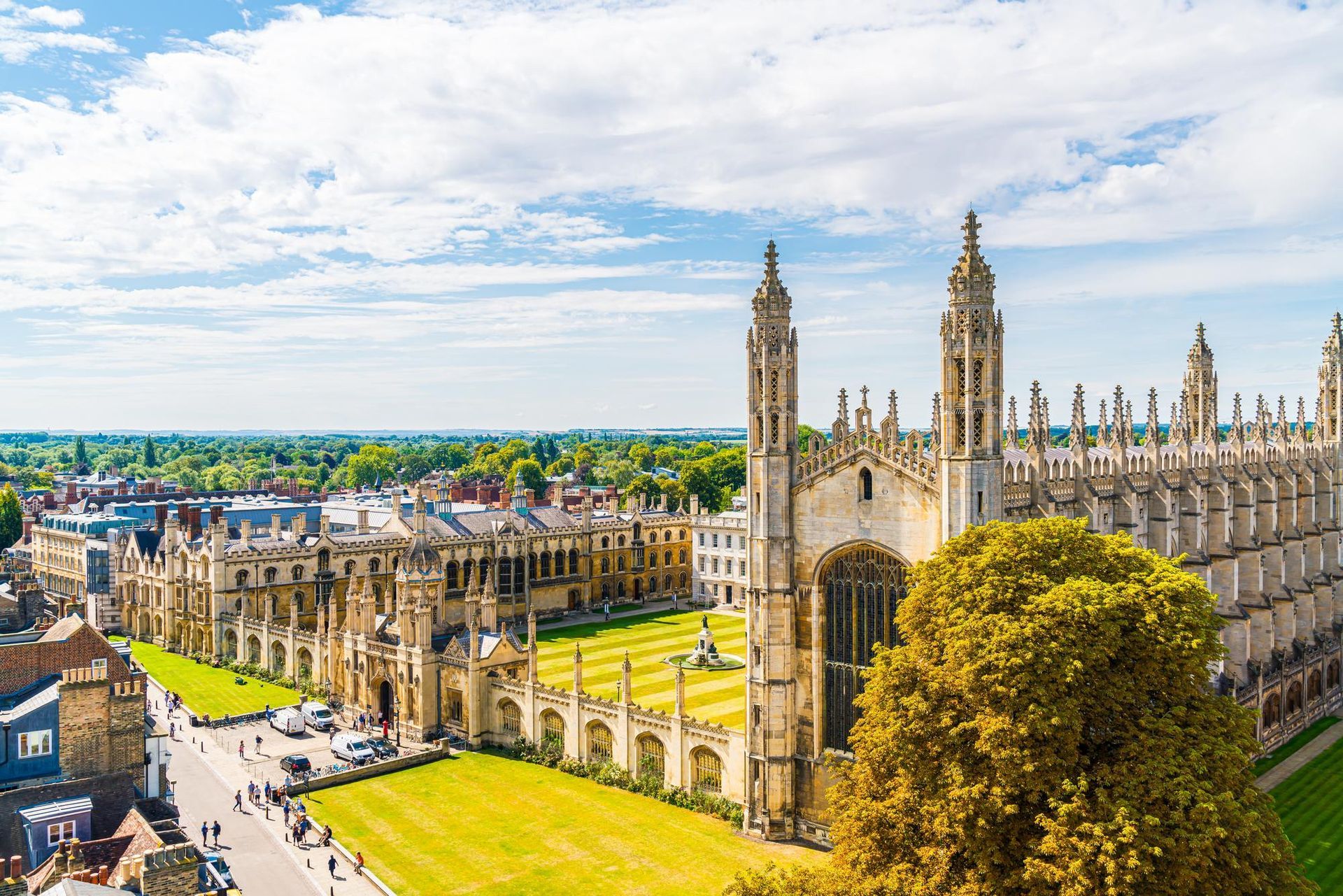 Aerial view of King's College Chapel, Cambridge, England, with green lawns, trees, and blue sky.