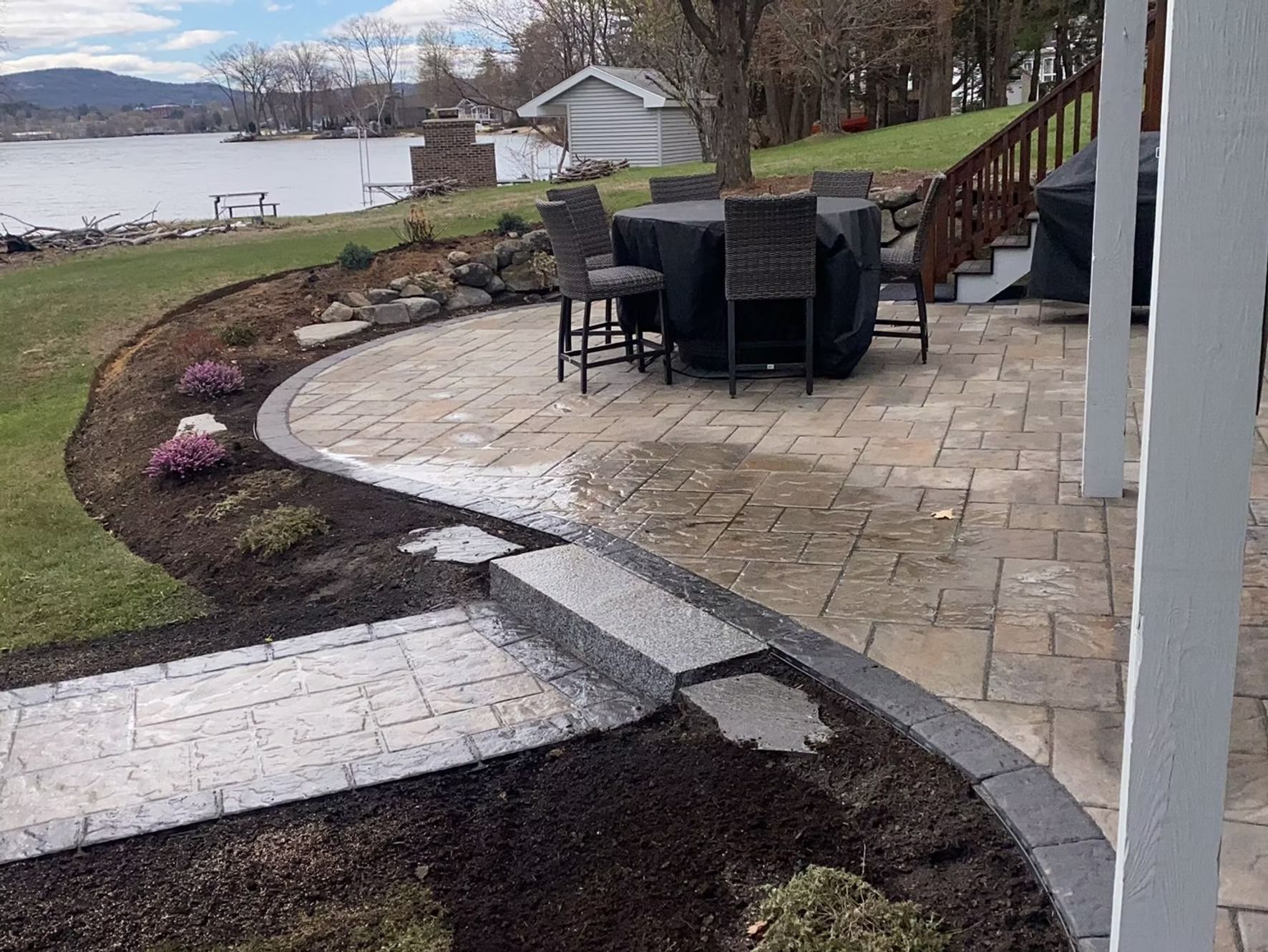 A patio with a table and chairs and a view of a lake.