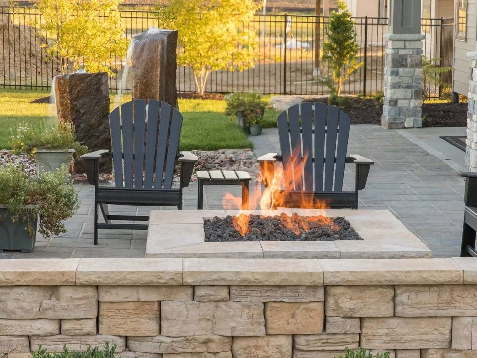 Two chairs are sitting next to a fire pit on a patio.