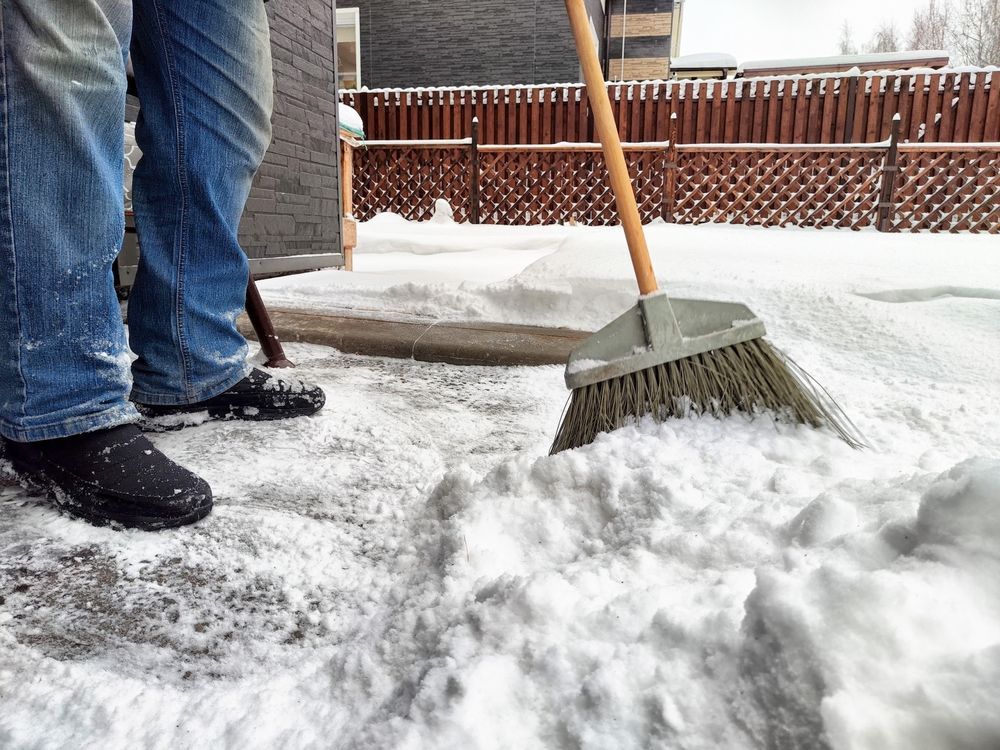A person is shoveling snow with a broom.