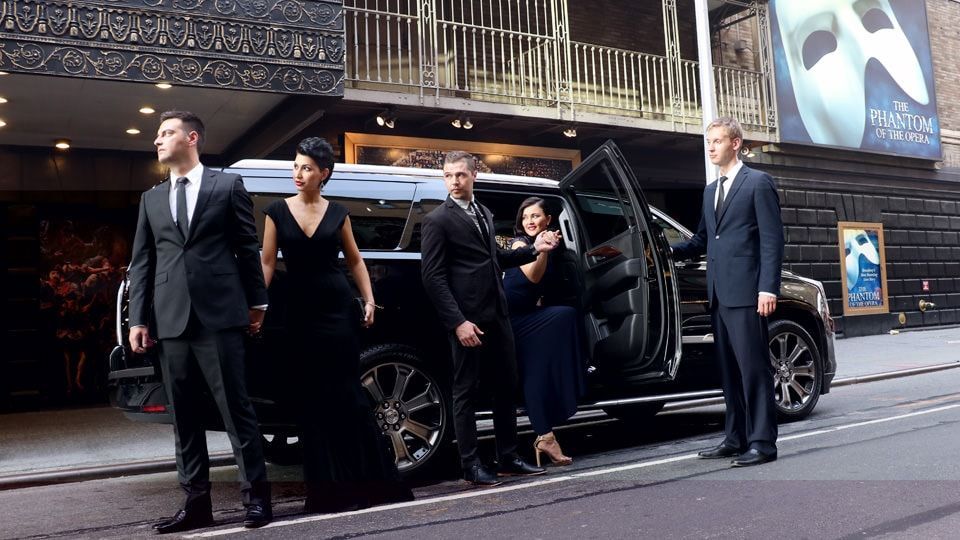 A group of people are standing in front of a car.