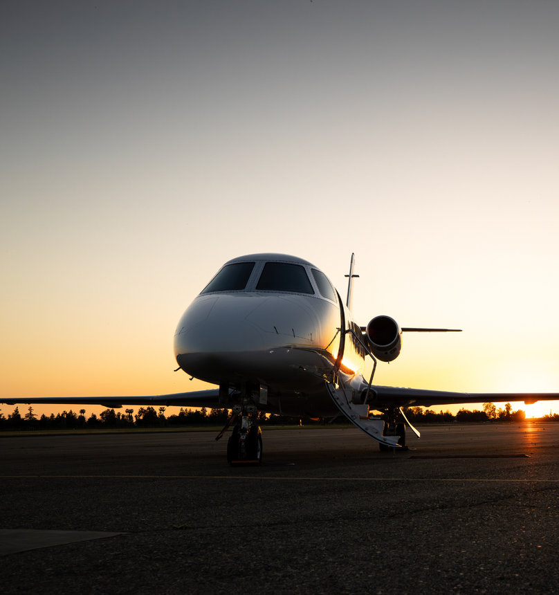 An airplane is parked on a runway at sunset