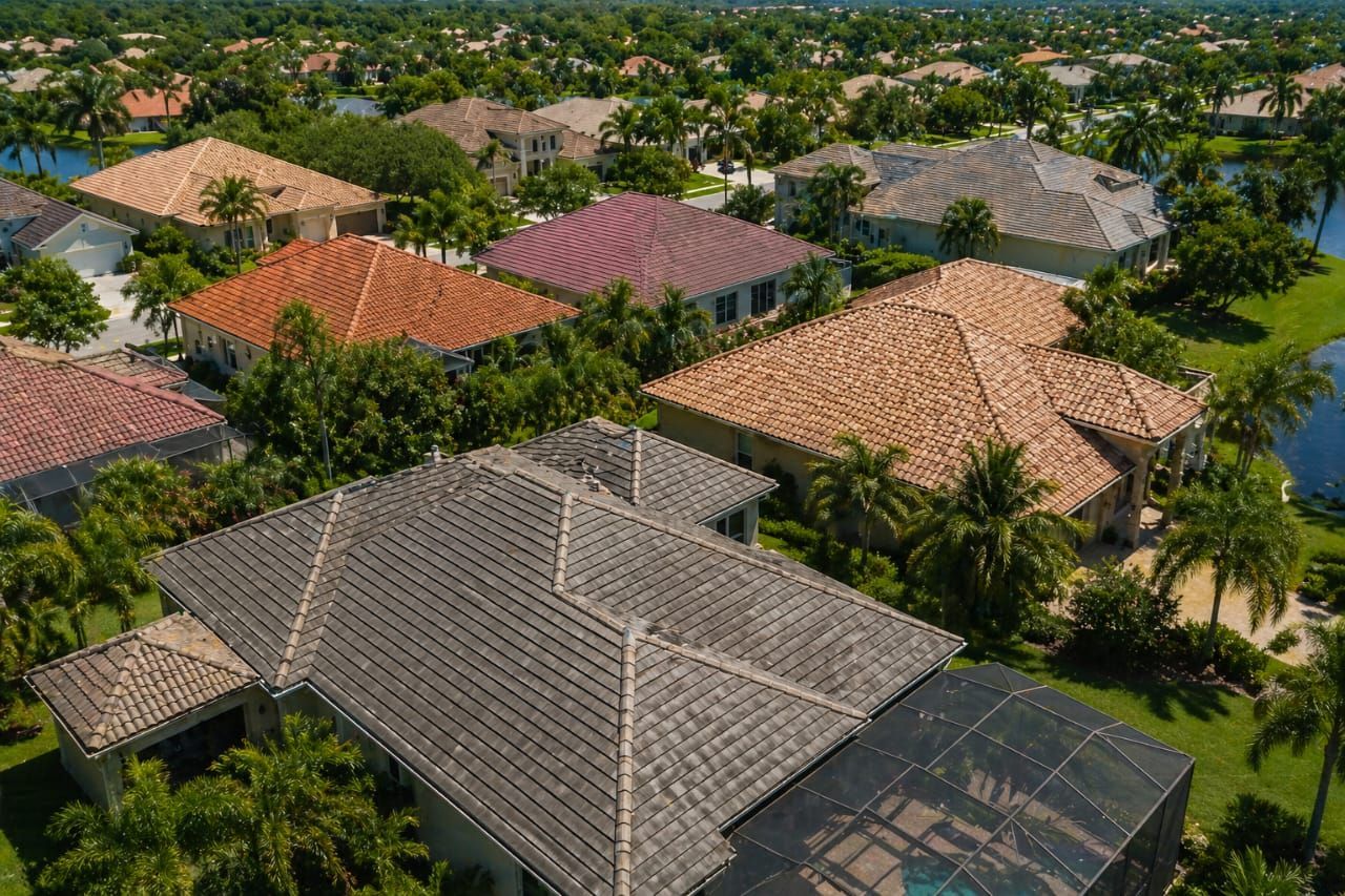 Aerial view of a suburban neighborhood with tiled rooftops and lush green trees.