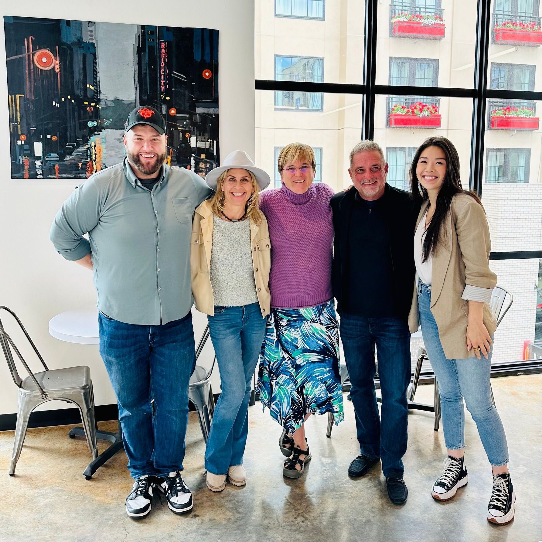 A group of people are posing for a picture in front of a window.