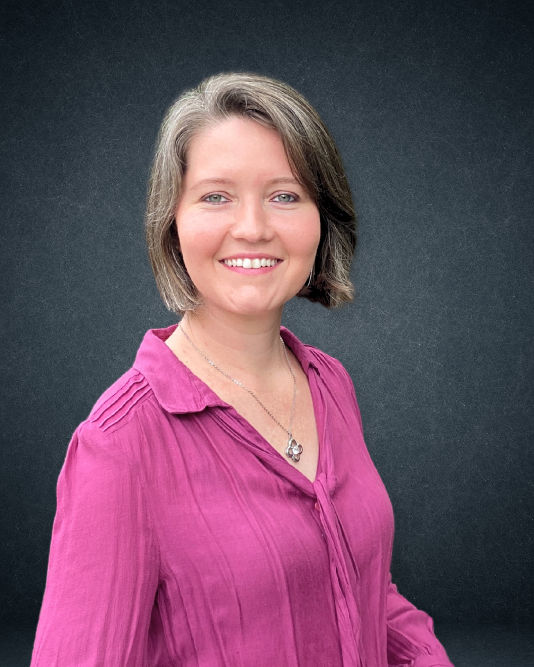 A woman in a purple shirt is smiling for the camera.