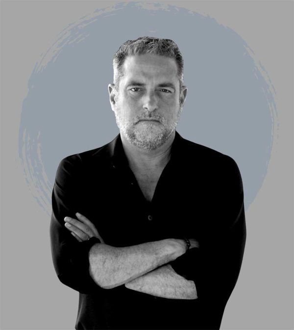 A man in a black shirt is standing with his arms crossed.
