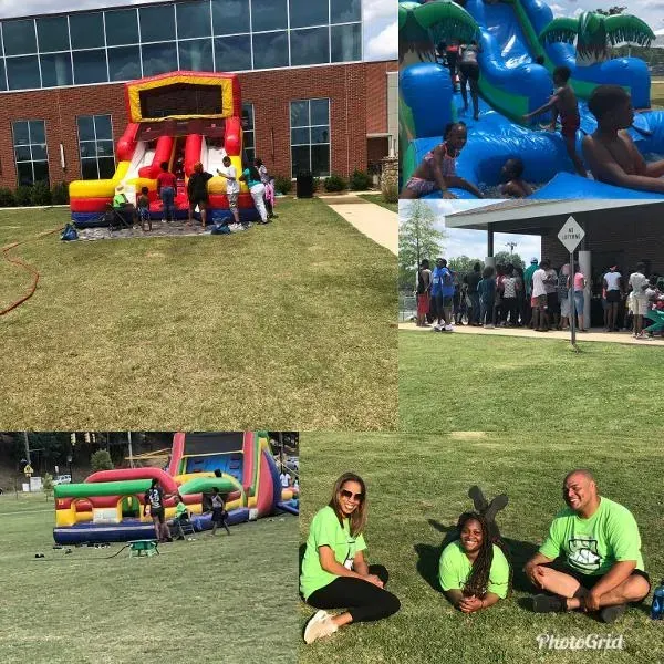 a group of people are sitting on the grass in front of a bouncy house .