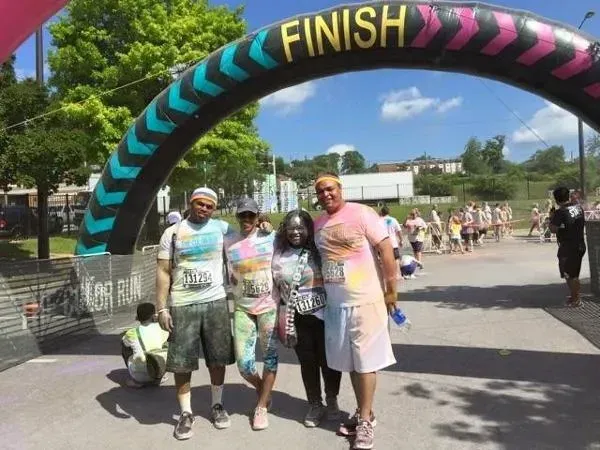 a group of people are standing in front of a finish line arch at a color run .