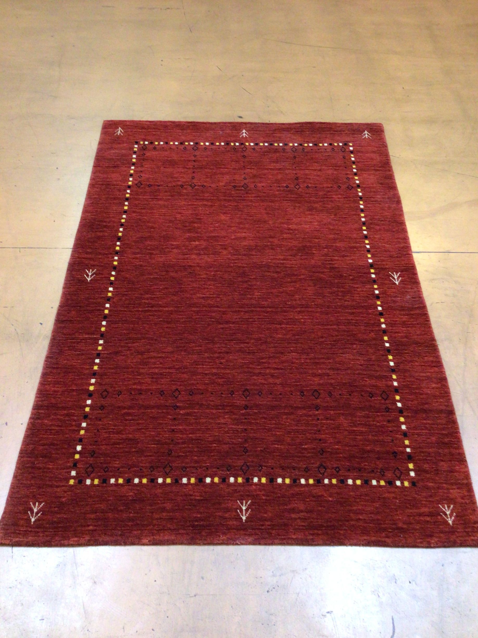 A red rug is sitting on a concrete floor.