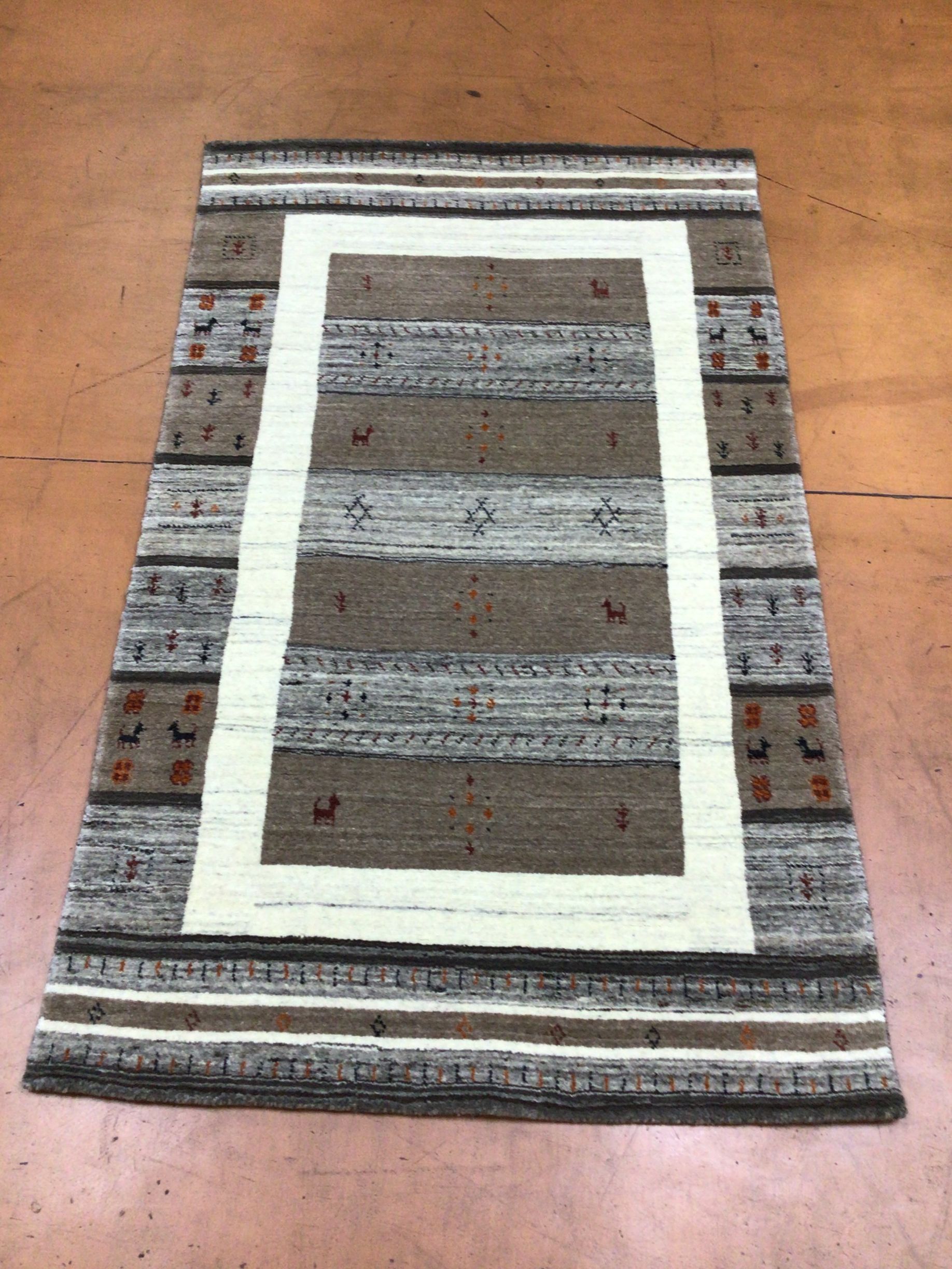 A rug with a white border is sitting on a wooden floor.