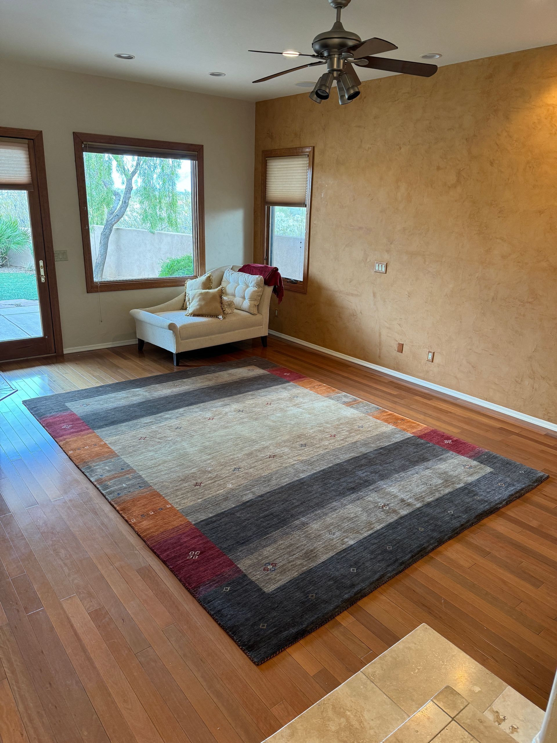 A living room with a rug , couch , and ceiling fan.