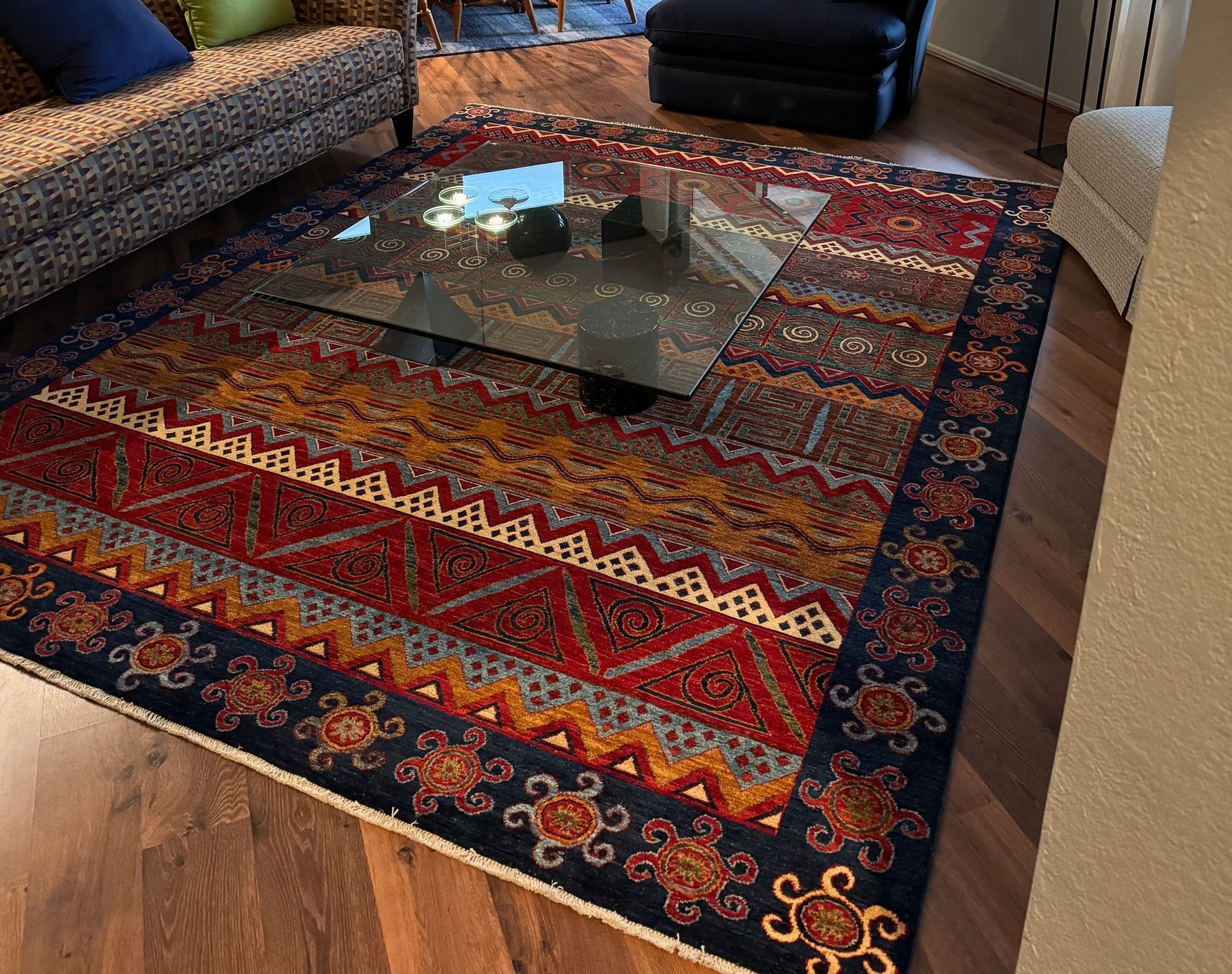 A living room with a rug and a glass coffee table