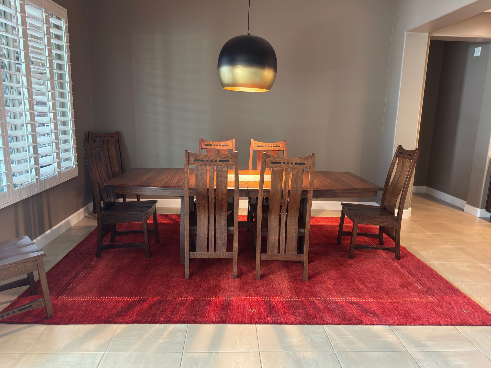 A dining room with a table and chairs and a red rug.