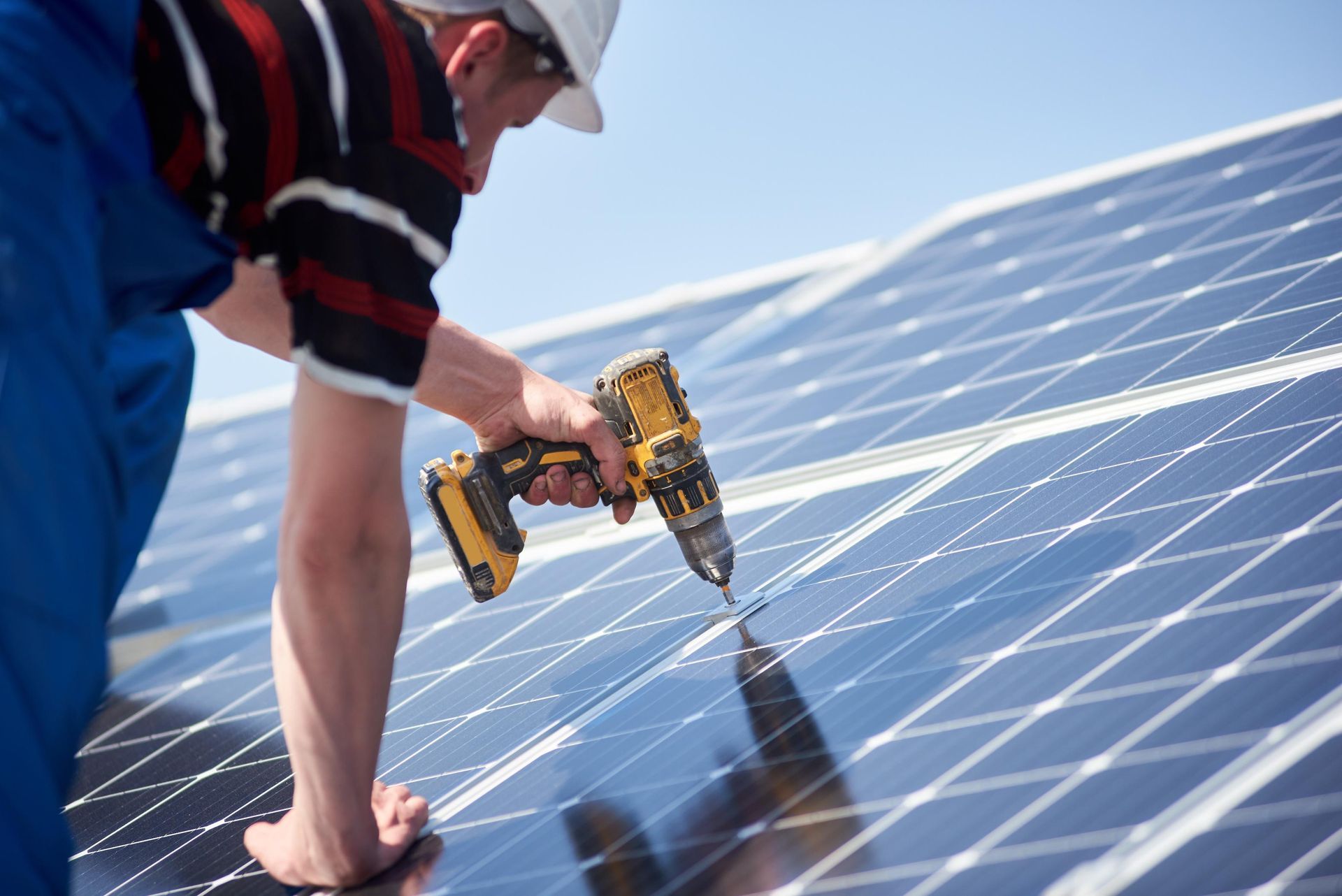 A man is working on a solar panel with a drill.