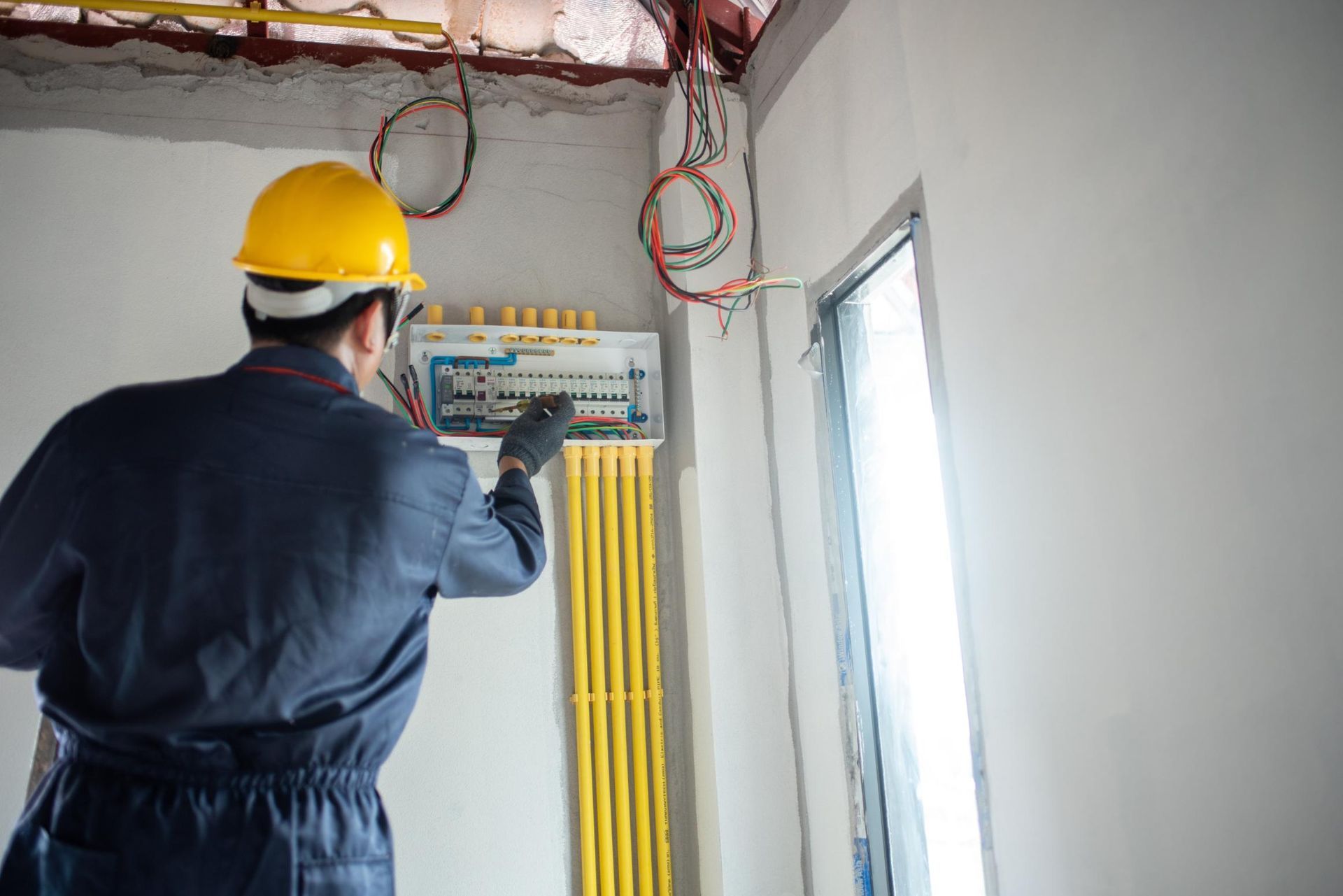 An electrician is working on an electrical box in a room.