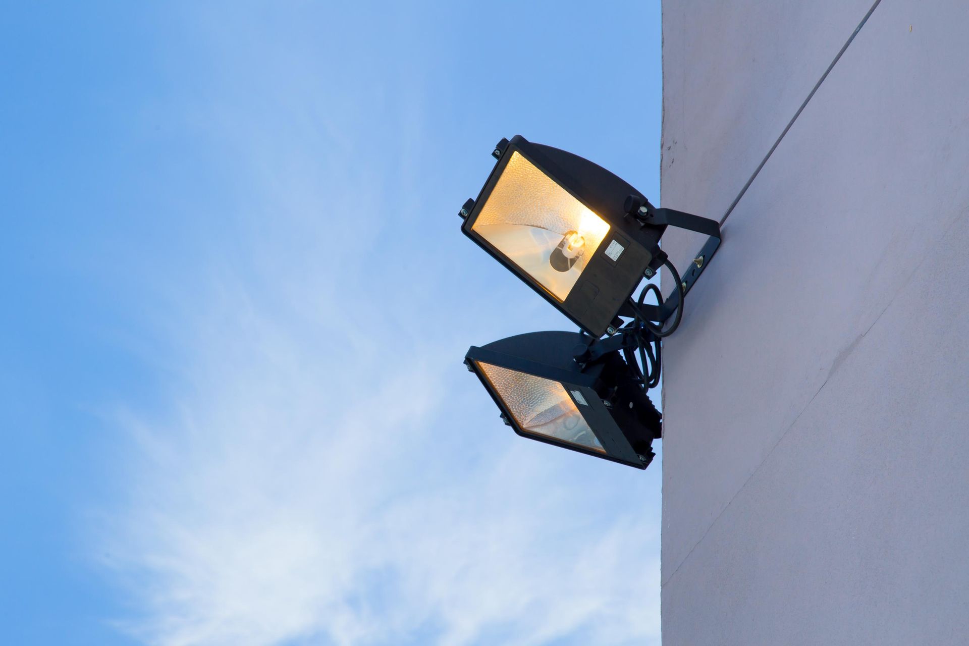 Two street lights are hanging from the side of a building.