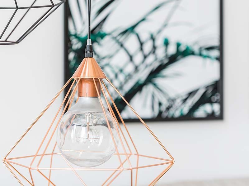 A light bulb is hanging from a copper geometric pendant light.