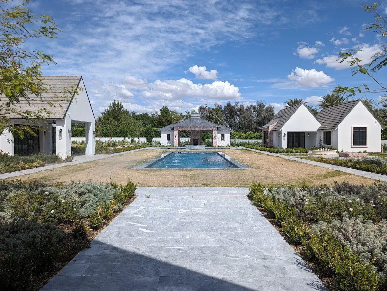 There is a large swimming pool in the middle of the yard surrounded by houses.