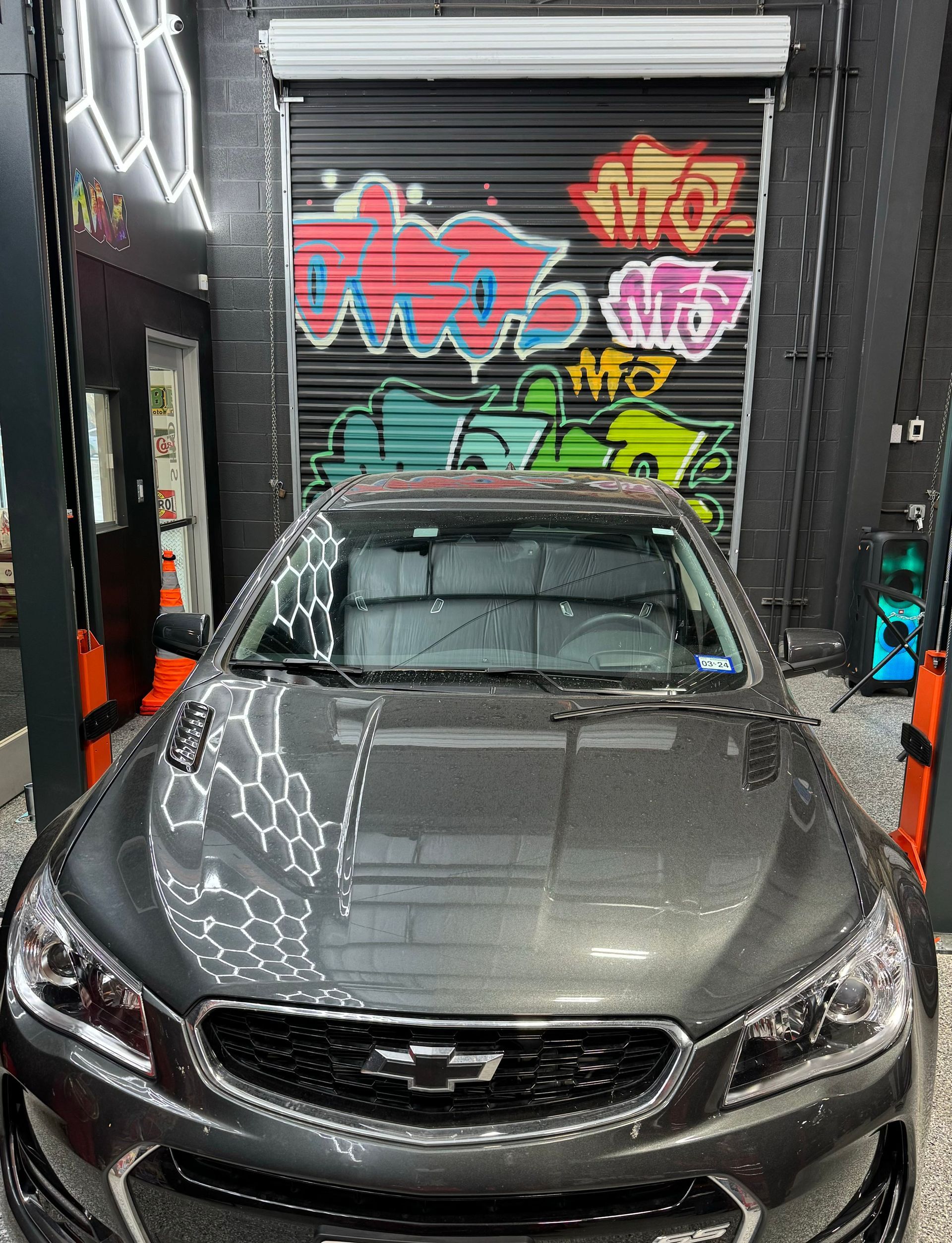 Gray Chevrolet SS in a garage with graffiti on the door. | Auto Motive