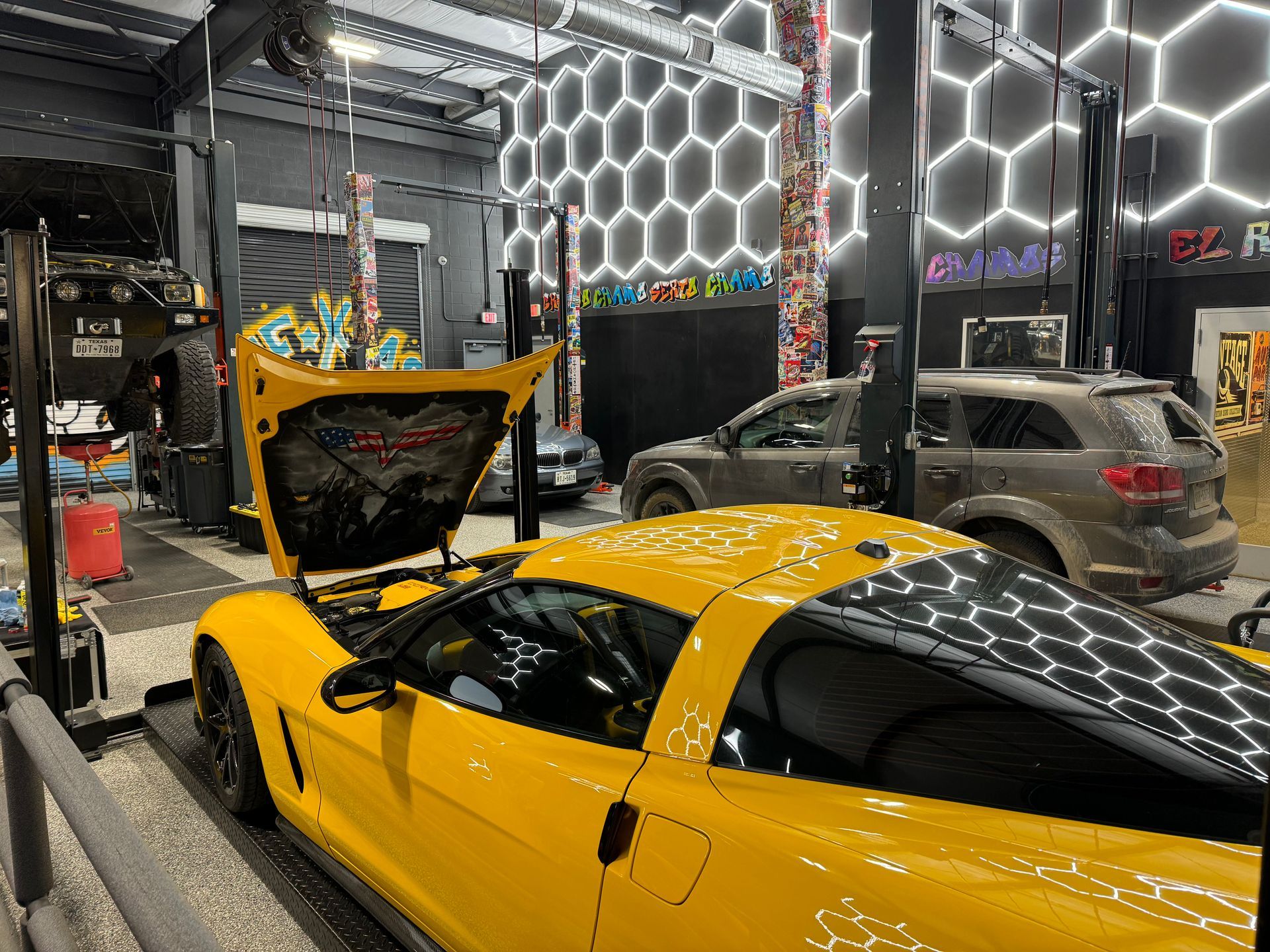 Yellow Corvette in a brightly lit auto repair shop. | Auto Motive