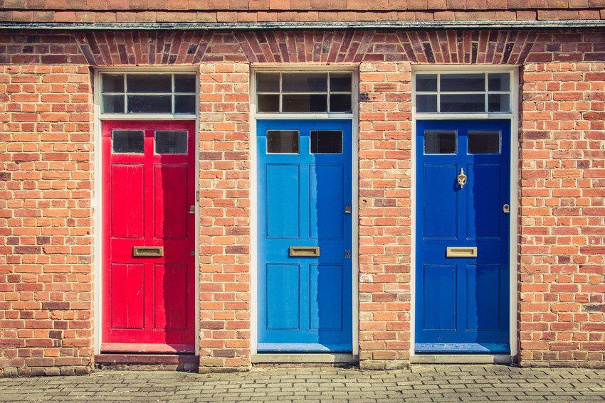 Three differently coloured front doors at the entrance of old English terraced houses