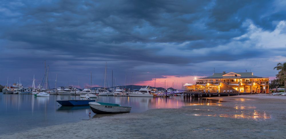 A Group of Boats Are Docked in a Harbor at Night — Port Stephens Removals & Storage In Soldiers Point, NSW